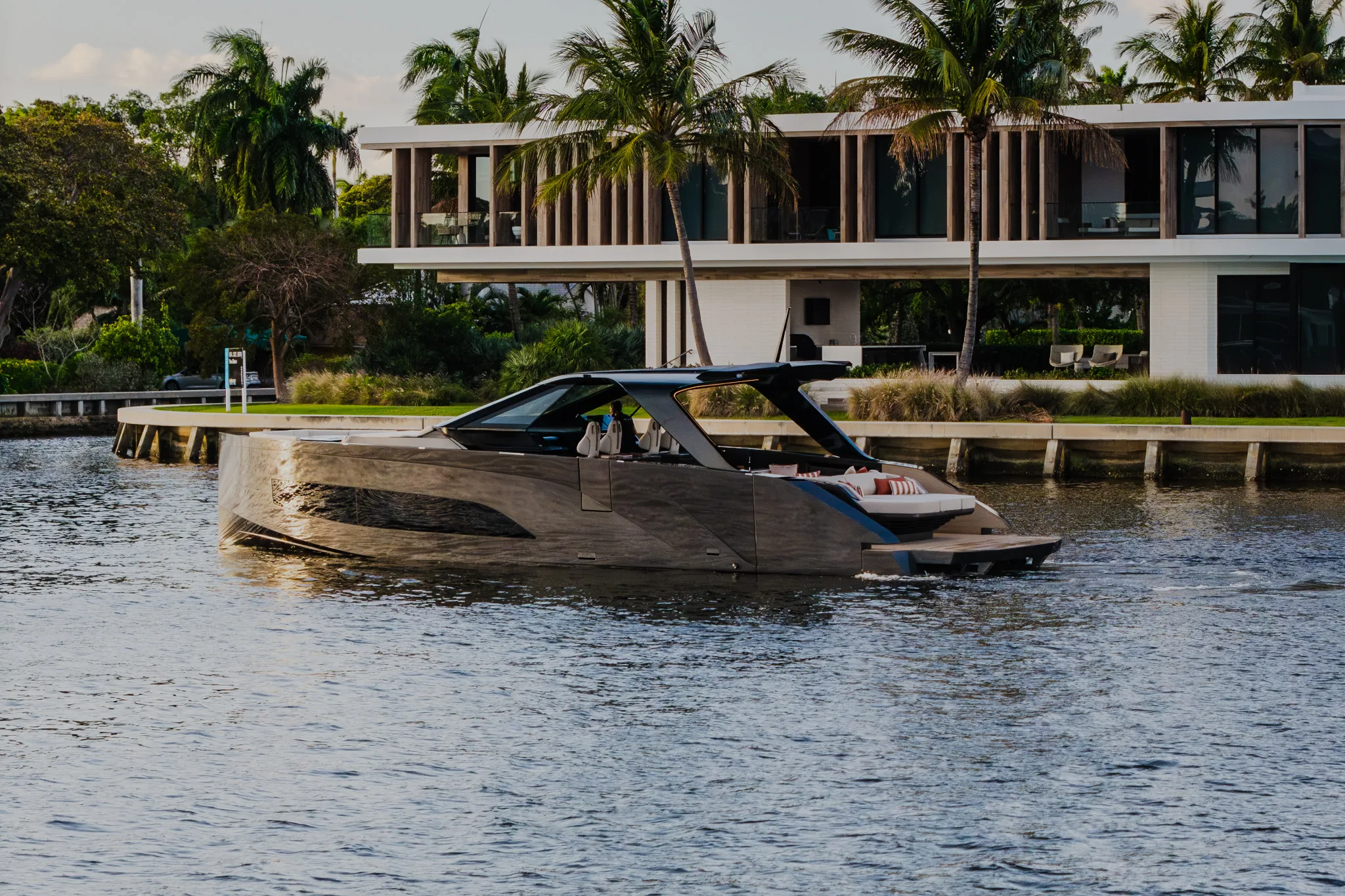 Manari 52 passing a contemporary waterfront home