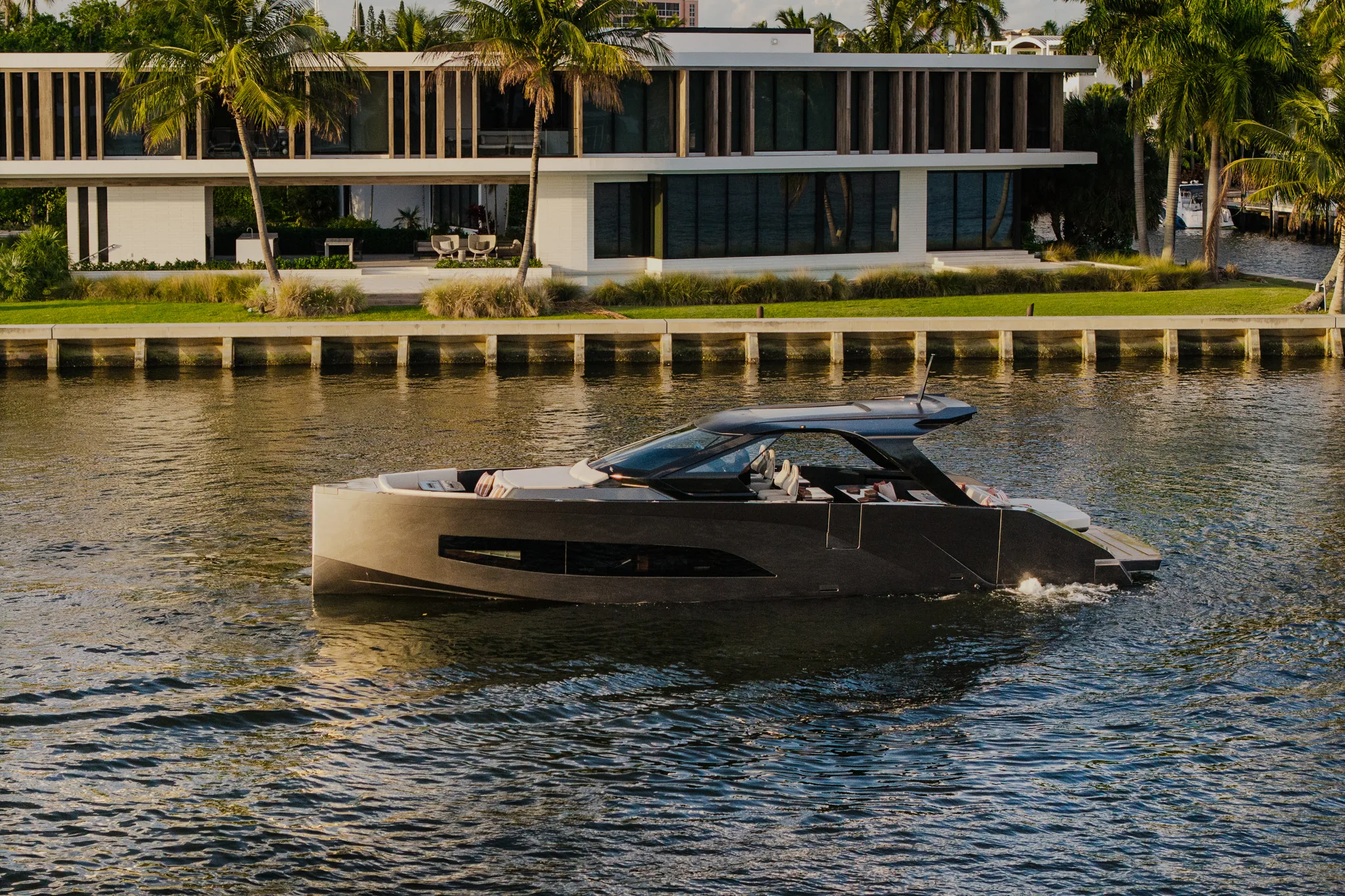 Manari 52 powerboat cruising past a waterfront residence